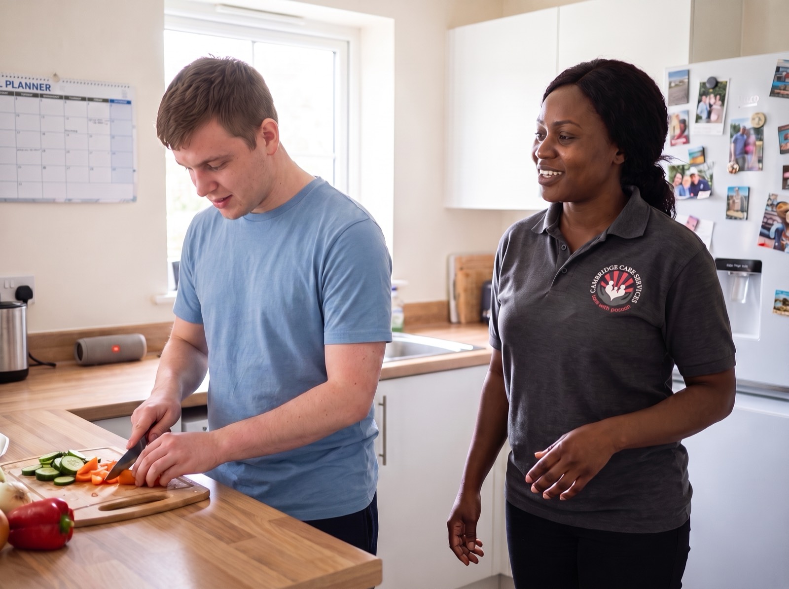 Young man cooking in his own flat with a Cambridge Care Services support worker alongside him in Cambridge supported living